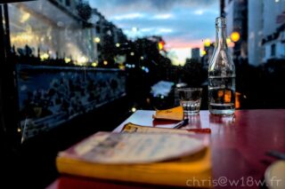 Table avec verre, bouteille, postit et livre sur fond de coucher de soleil en ville