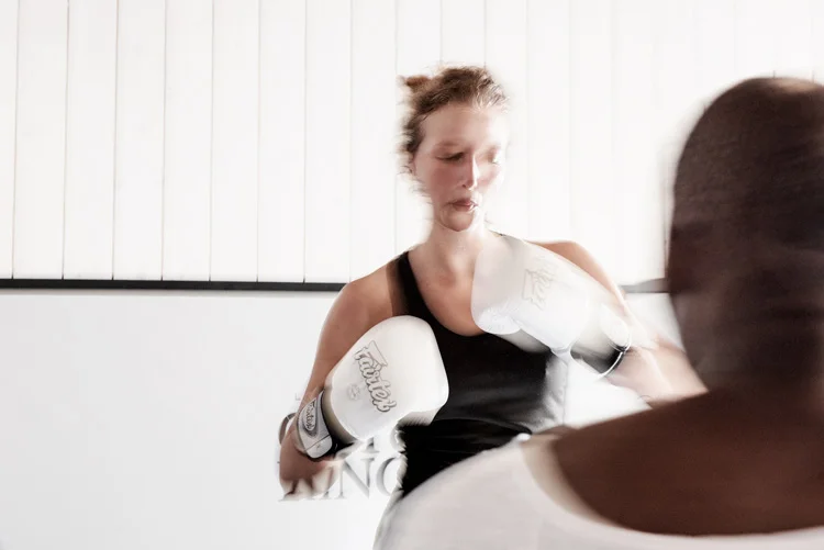 Une femme s'entraine dans une salle avec des gant de boxe