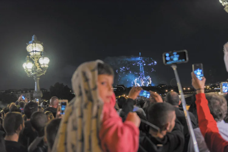 une foule regarde la tour Eiffel et ses feux d'artifice